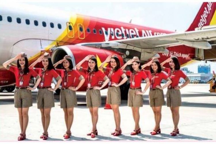 Para pramugari VietJet mengenakan sragam setelan baju merah berkerah dan celana pendek coklat.