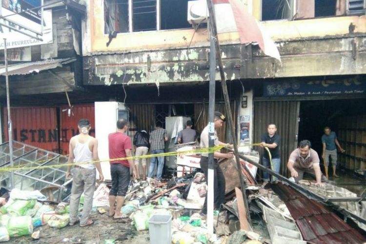 Polisi memasang garis pembatas di lokasi kebakaran minimarket yang menewaskan satu keluarga di Jalan Lintas Medan-Banda Aceh, Desa Lhok Dalam, Kecamatan Peureulak, Kabupaten Aceh Timur, Minggu (7/10/2018)