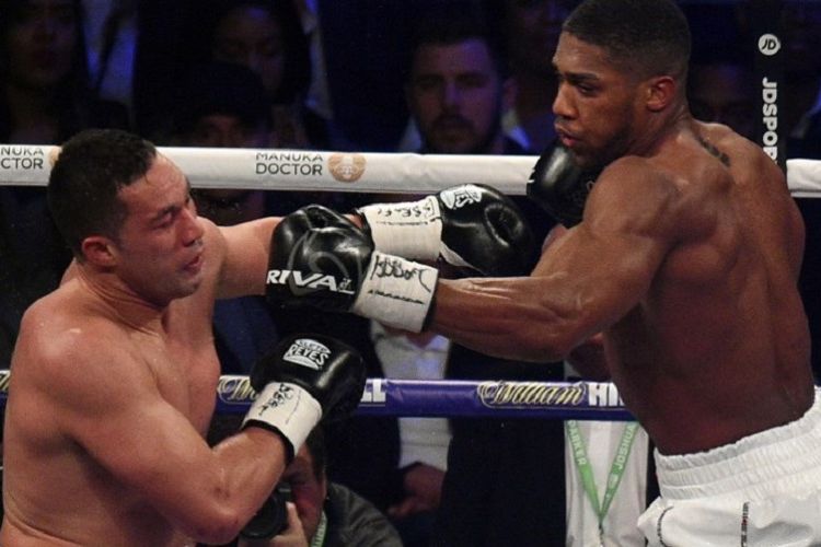 Anthony Joshua melepas jab ke arah Joseph Parker pada pertandingan tinju kelas berat di Cardiff, Sabtu (31/3/2018). 