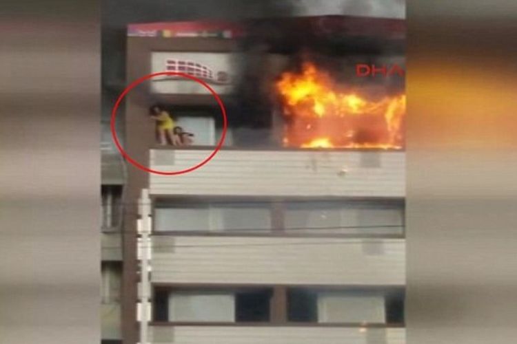 Seorang perempuan berbaju kuning (dilingkari) berdiri di tepian balkon Hotel Alican, Izmir, Turki yang terbakar.