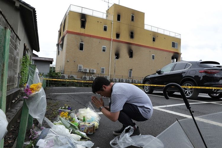 Seorang warga berdoa di luar gedung studio animasi, Kyoto Animation, yang terbakar, Kamis (18/7/2019), dan menewaskan hingga 33 orang.