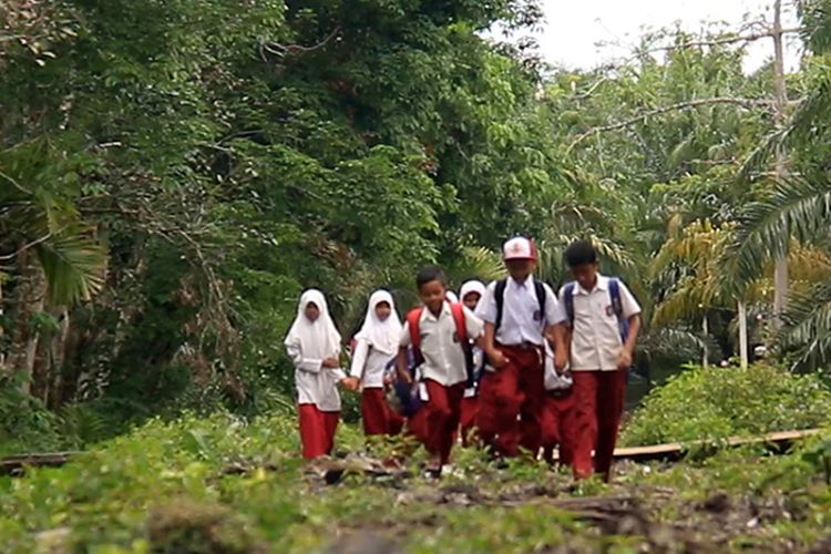 Pelajar sekolah dasar di Desa Pasir Putih, Aceh Barat, Nanggroe Aceh Darussalam, melintasi jalan semak blukar dengan berjalan kaki menuju ke sekolah, Kamis (13/4/2017)