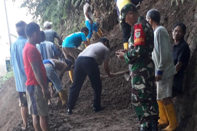 Kepolisian dan TNI beserta sejumlah warga turut membersihkan material longsor yang menutupi badan jalan, Jumat (26/4/2019)