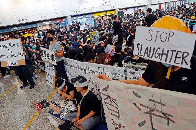 Massa pengunjuk rasa pro-demokrasi ketika melakukan aksinya setelah seorang perempuan tertembak di mata dalam aksi protes di Bandara Internasional Hong Kong, Senin (12/8/2019).
