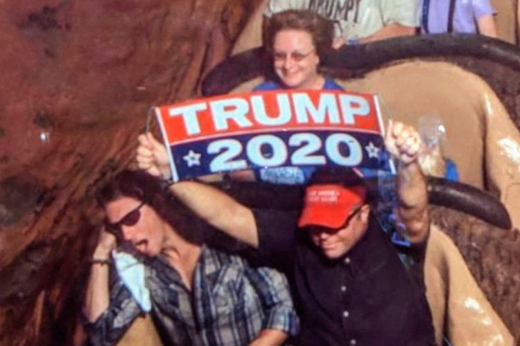 Mantan Marinir AS, Dion Cini (kanan) mengangkat spanduk bertuliskan Trump 2020 saat menaiki salah satu wahana di Walt Disney World.
