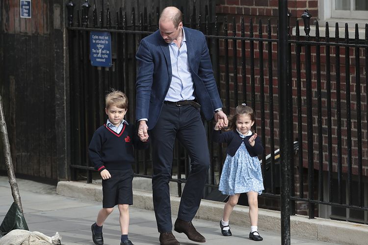 Putri Charlotte (kanan) melambaikan tangan pada media saat berjalan bersama saudara lelakinya, Pangeran George (kiri) dan ayah mereka, Pangeran William, saat hendak mengunjungi anak ketiga William dan Kate Middleton di Rumah Sakit St Mary, London, Senin (23/4/2018) waktu setempat. Anak ketiga tersebut merupakan pemegang kelima tahta Kerajaan Inggris setelah Pangeran Charles, William, George dan Putri Charlotte.