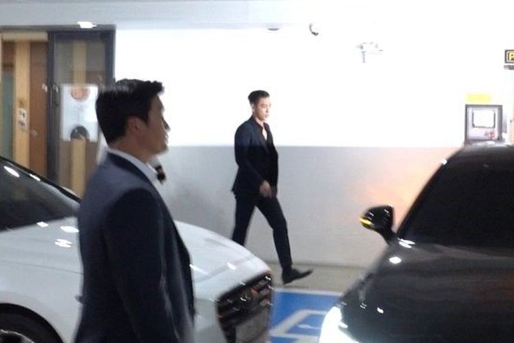 Member boyband BIGBANG T.O.P (kanan) berjalan ke mobilnya di area parkir kantor pemerintah Kota Yongsan setelah ia mengakhiri masa wajib militernya, Sabtu (6/7/2019).