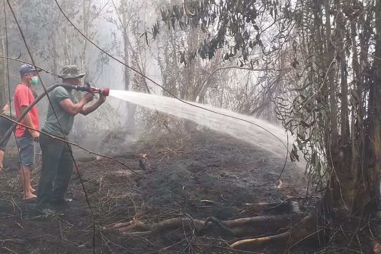 Petugas TNI dan warga memadamkan api karhutla yang mendekati rumah warga di Desa Rimbi Panjang, Kecamatan Tambang, Kabupaten Kampar, Riau, Selasa (17/9/2019)