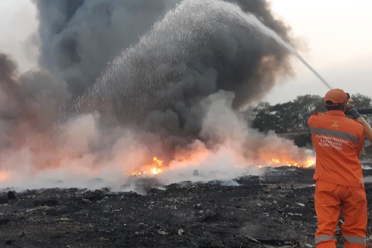 Petugas PPSU membantu memadamkan api di yang membakar sebuah pabrik dikawasan Kamal, Kalideres, Jakarta Barat, Kamis (19/9/2019) malam