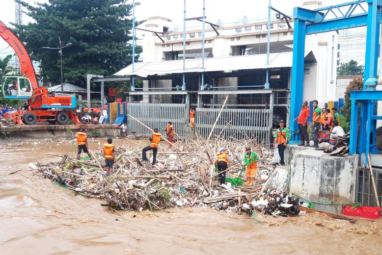 Petugas saat membersihkan sampah di Pintu Air Manggarai, Jumat (26/4/2019)