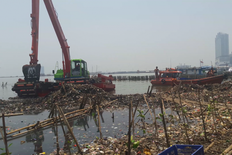 Alat berat dan kapal disiagakan untuk mengangkut sampah dari lautan sampah di Muara Angke, Jakarta Utara.