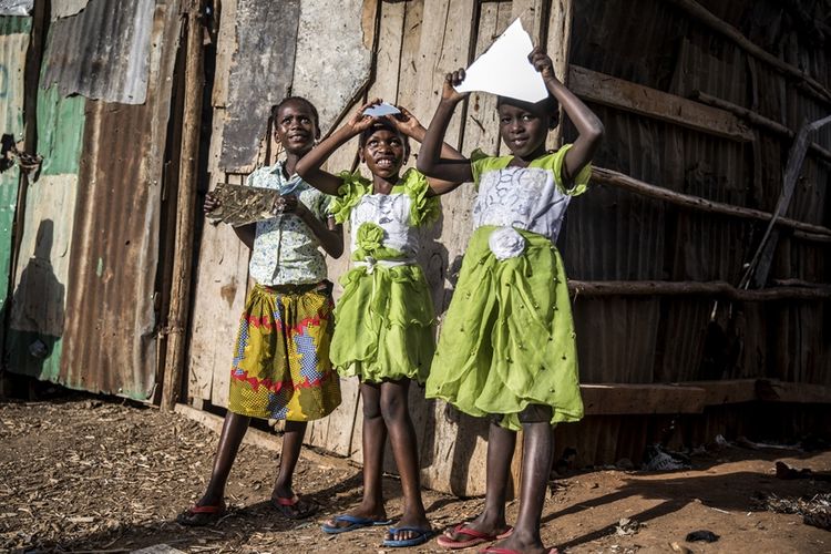 Anak-anak perempuan di Kenya bermain dengan pecahan cermin di kawasan kumuh di Nairobi.