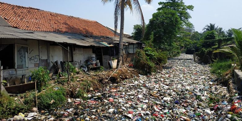 Bangunan liar di bantaran Kali Bahagia atau Kali Busa di Kecamatan Babelan, Kabupaten Bekasi yang alirannya tertutup sampah plastik.