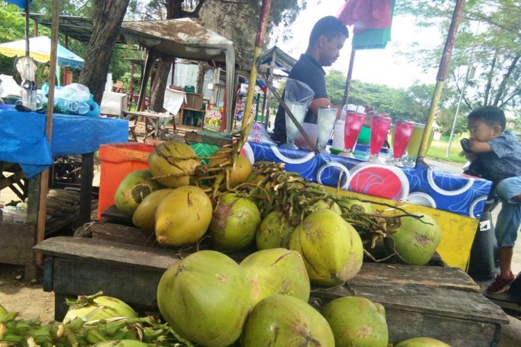 Pedagang mengupas kelapa muda di Jalan Lingkar Stadion Tunas Bangsa, Kota Lhokseumawe, Minggu (7/1/2018).