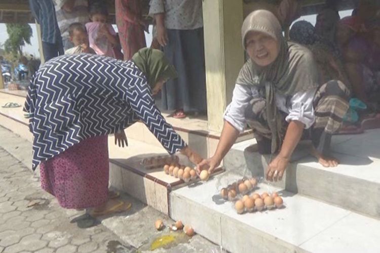 Keluarga Penerima Manfaat (KPM) program Bantuan Pangan Non-Tunai (BPNT), mengecek kualitas telur yang mereka terima di Kantor Desa Morosunggingan, Kecamatan Peterongan, Kabupaten Jombang, Minggu (25/11/2018).