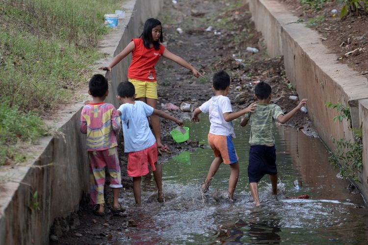 Anak-anak menggunakan selokan air di Jalan Yos Sudarso, Jakarta Utara, untuk bermain, Minggu (23/7/2017). Pengawasan orang tua pada anak perlu dilakukan untuk mengurangi resiko kekerasan terhadap mereka.