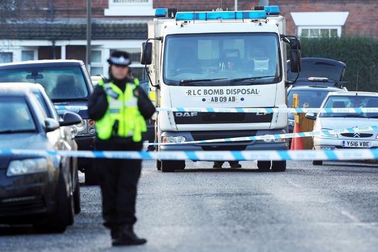 Seorang petugas polisi berjaga di kawasan perumahan Chesterfield, Derbyshire dengan unit penjinak bom didatangkan usai penangkapan terduga teroris, Selasa (19/12/2017) dini hari.