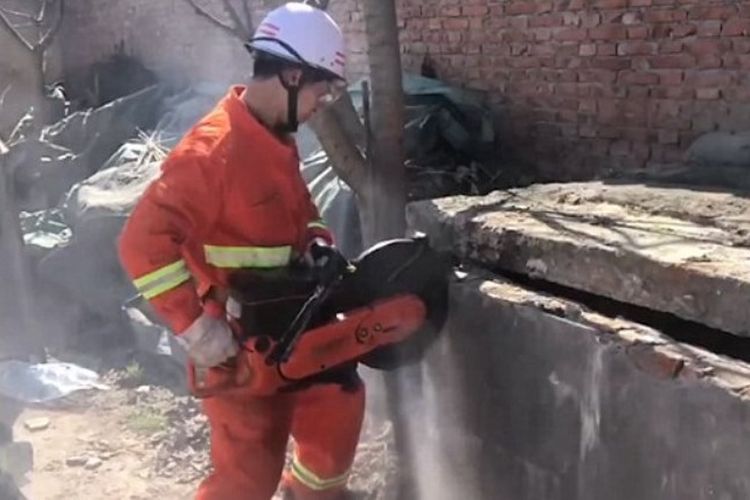 Seorang petugas pemadam kebakaran menggunakan gergaji mesin membongkar penutup septik tank untuk menyelamatkan seorang bayi.