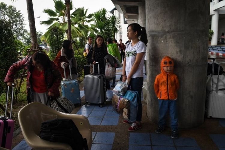 Turis asal China menunggu informasi di bandara Surat Thani setelah otoritas menangguhkan penerbangan akibat badai tropis Pabuk, di provinsi Surat Thani, Thailand, Jumat (4/1/2019). (AFP/LILLIAN SUWANRUMPHA)