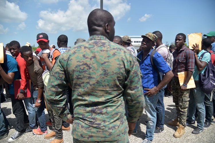 Seorang personel militer Haiti mengawasi barisan para pemuda yang mendaftar untuk bergabung dengan angkatan bersenjata yang kembali dibentuk setelah dibubarkan 22 tahun lalu.