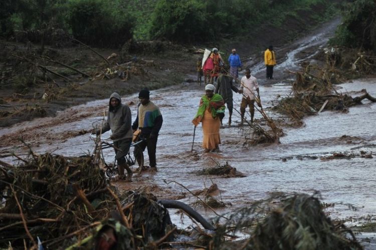 Penduduk Kenya berusaha menyeberangi wilayah yang tersapu gelombang air akibat jebolnya bendungan Patel di Solai, Nakuru County. Hujan deras membuat bendungan Patel jebol pada Rabu (9/5/2018) malam waktu setempat. (AFP/Tony Karumba)