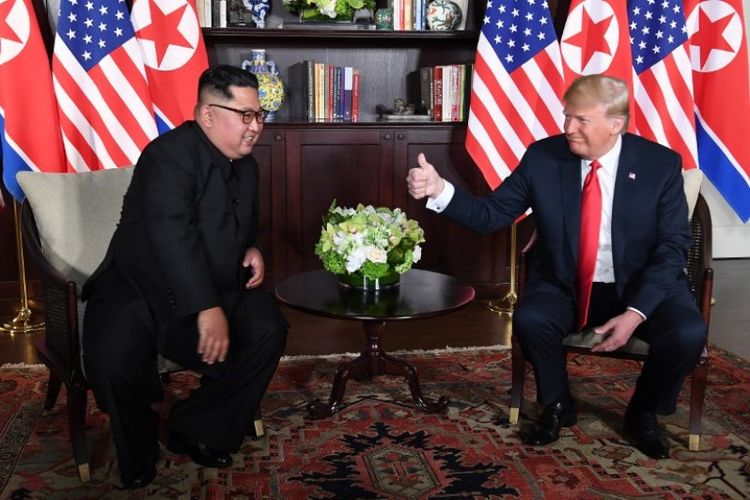 Presiden Amerika Serikat Donald Trump dan pemimpin Korea Utara Kim Jong Un duduk bersebelahan untuk menyapa media di Hotel Capella, Singapura, Selasa (12/6/2018). (AFP/Saul Loeb)
