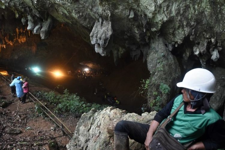 Tim penyelamat terlihat di depan gua Tham Luang di Taman Hutan Non Khun Nam Nang di Chiang Rai, Tabu (27/6/2018). Mereka berupaya menyelamatkan 12 remaja dan pelatih mereka yang hilang selama beberapa hari di dalam gua. (AFP/Lillian Suwanrumpha)