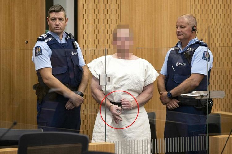 Brenton Tarrant, teroris penembakan masjid Selandia Baru membentuk gestur OK yang merupakan lambang supremasi kulit putih dengan jarinya ketika masuk untuk menjalani sidang perdana Sabtu (16/3/2019).