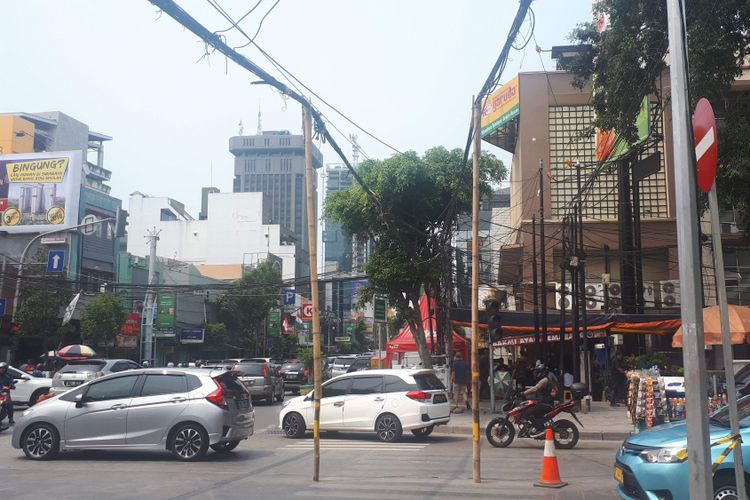 Kabel listrik yang melintang di perempatan Jalan KH Hasyim Asyari tampak semrawut pada Selasa (6/11/2018).  Pantauan Kompas.com, ada dua batang bambu yang ditempatkan di tengah jalan untuk menopang kabel agar tidak jatuh ke tanah.