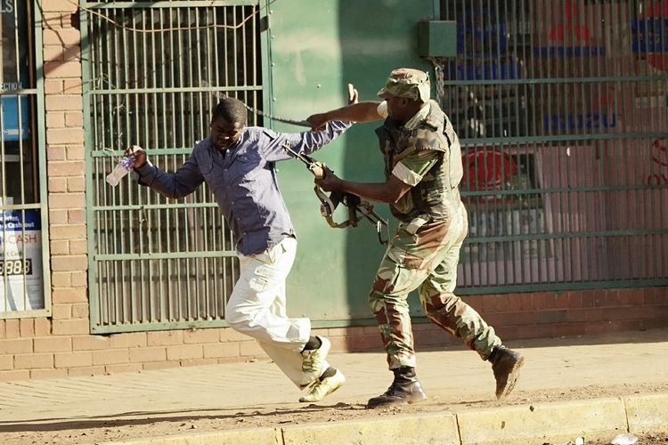 Seorang tentara Zimbabwe memukul pendukung oposisi di jalanan Harare Rabu (1/8/2018). Bentrokan terjadi antara pendukung oposisi dan pasukan setelah massa menyebut Pemilihan Umum di Zimbabwe telah dicurangi.