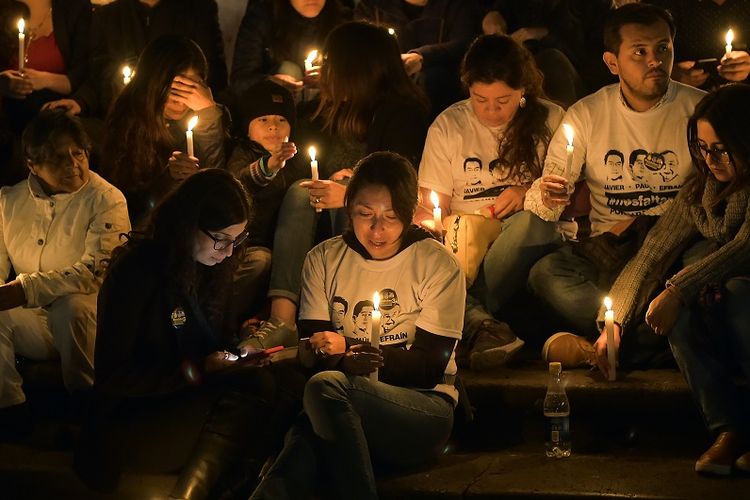 Keluarga dan kerabat jurnalis Ekuador Javier Ortega, fotografer Paul Rivas, dan pengemudi mereka Efrain Segarra yang tewas setelah disandera selama tiga pekan oleh pemberontak FARC Kolombia, menyalakan lilin dan berdoa di depan Katedral Metropolitan Cathedral, Quito, Jumat (13/4/2018). 
