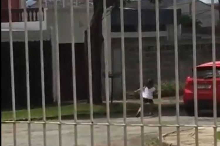 Dalam foto yang diambil dari sebuah video ini terlihat anak perempuan berusia lima tahun mengejar sebuah mobil berwarna merah yang dikemudikan ibunya.