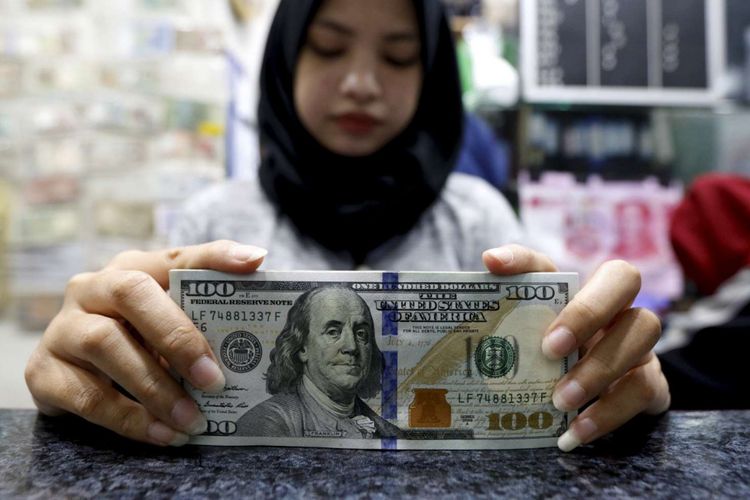 Petugas menunjukan pecahan dollar Amerika di salah satu gerai penukaran mata uang di Kwitang, Jakarta, Jumat (29/6/2018). Nilai tukar rupiah terhadap dollar AS pada perdagangan Jumat (29/6/2018) siang berada pada level Rp 14.360.