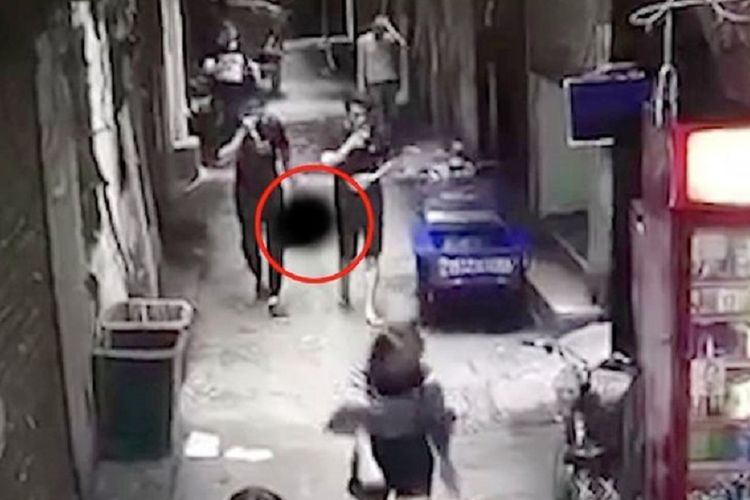 Dalam foto yang diambil dari rekaman CCTV ini terlihat Zhang (kiri) berjalan santai di sebuah gang yang ramai sambil menenteng potongan kepala istrinya.