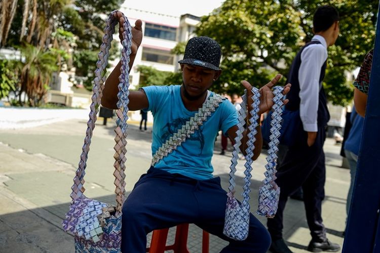 Wilmer Rojas (25) menunjukkan kreasi tas yang terbuat dari uang kertas bolivar yang dijualnya. Nilai mata uang yang sangat rendah membuatnya berkreasi untuk membuat uang kertas lebih berharga.