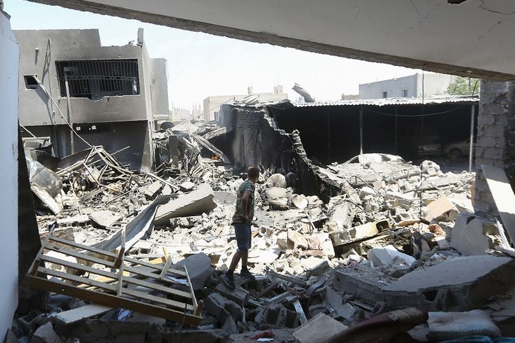 Anggota pasukan pro pemerintah nasional GNA memeriksa bangunan di kompleks militer Yarmouk, selatan Tripoli, yang hancur akibat serangan udara pada 1 Juli 2019.