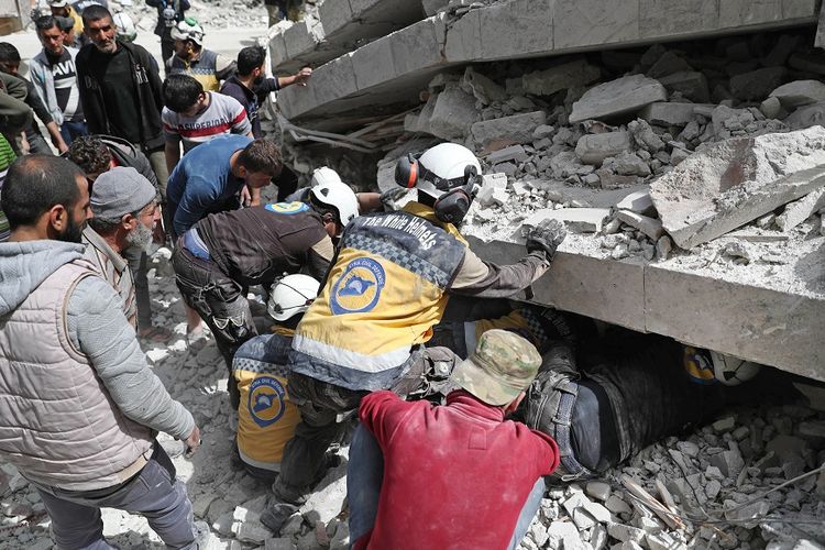 Petugas dari Pertahanan Sipil Suriah (SCD) atau Helm Putih, memeriksa reruntuhan bangunan yang hancur akibat serangan udara yang dilancarkan pasukan rezim Suriah dan sekutunya, Rusia, ke kawasan Idlib, 24 April 2019.