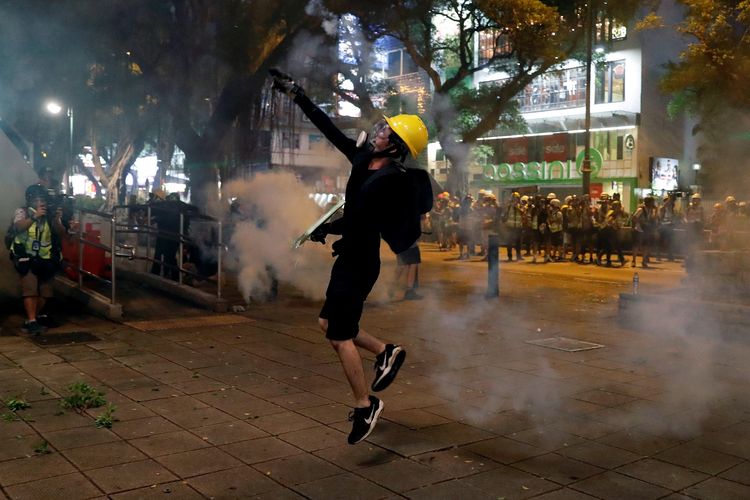 Seorang pengunjuk rasa anti rancangan undang-undang ekstradisi melempar gas air mata saat berunjuk rasa di Tsim Sha Tsui di Hong Kong, China, Minggu (11/8/2019).