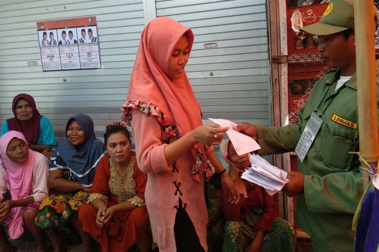 Salah satu warga Dusun Pandian, Desa Dharma, Kecamatan Camplong, Kabupaten Sampang, menyerahkan surat undangan atau form C6 kepada petugas TPS dalam pemungutan suara ulang (PSU) Sabtu (27/10/2018)