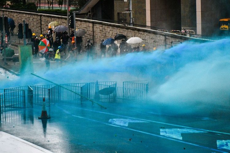 Air berwarna biru yang ditembakkan petugas keamanan Hong Kong menggunakan meriam air dalam membubarkan massa demonstrasi, Sabtu (31/8/2019).