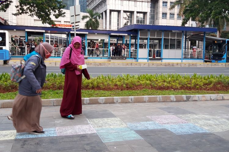Pejalan kaki bermain engkle di trotoar Jalan Sudirman, Jakarta Pusat, Jumat (17/5/2019)
