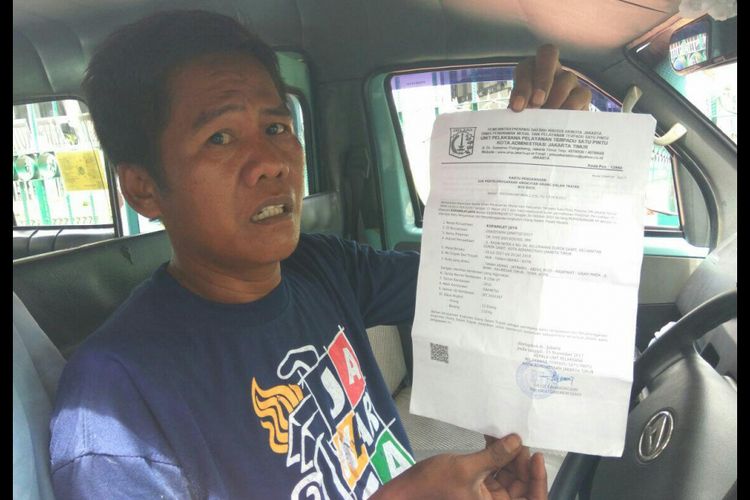 John seorang sopir angkot sambil menunjukan selembar kertas perpanjangan trayek dari Dishub.