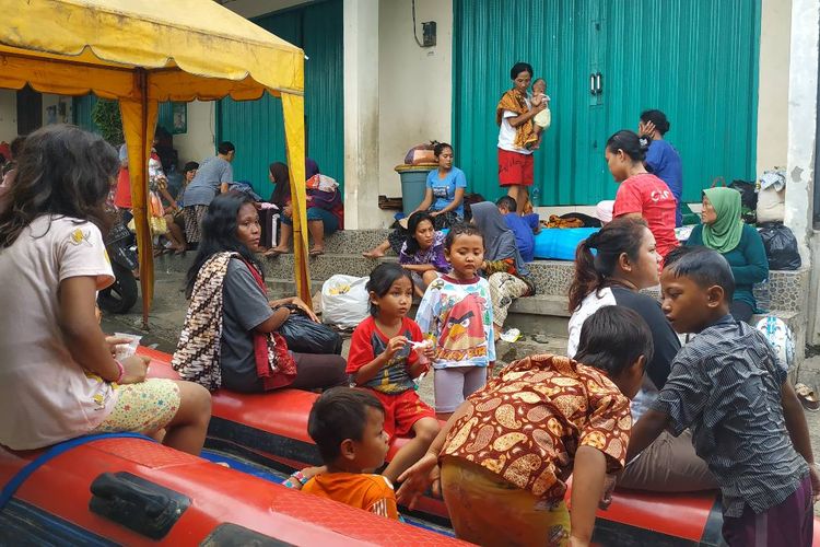 Sejumlah warga mengungsi sementara di emperan kios menunggu surutnya banjir yang merendam pemukiman di Pejaten Timur, Pasar Minggu, Jakarta Selatan Jumat (26/4/2019). 
