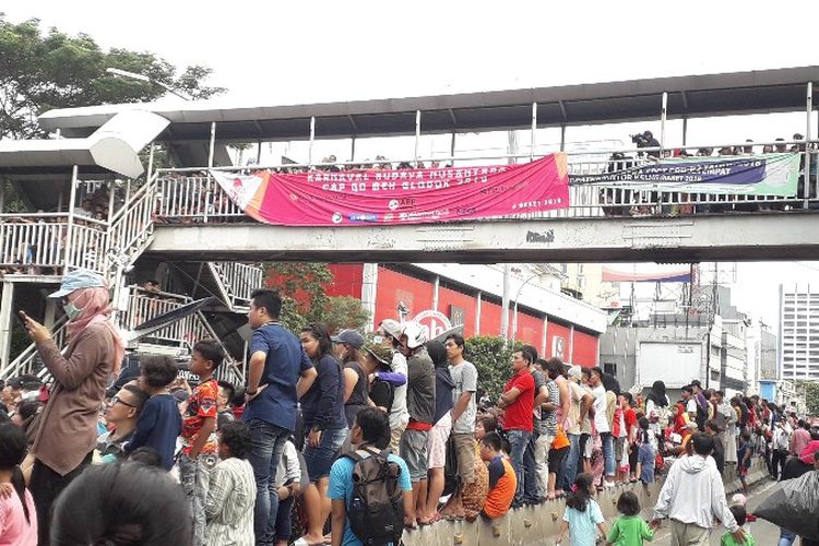Pengunjung Karnaval Cap Go Meh Glodok, Jakarta Barat pada Minggu (4/3/2018) membludak hingga menaiki Jembatan Penyebrangan Orang dan beton pembatas jalan. 