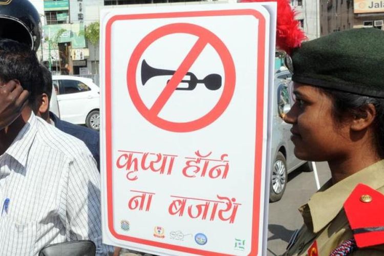 Petugas perempuan membawa tanda yang dilarang membunyikan klakson. Di Mumbai, diterbitkan peraturan yang melarang suara klakson terlalu keras.