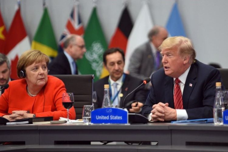 Kanselir Jerman Angela Merkel (kiri) mendengarkan Presiden AS Donald Trump, selama sesi pleno pada hari kedua KTT Pemimpin G20, di Buenos Aires, Argentina, Sabtu (1/12/2018). (AFP)
