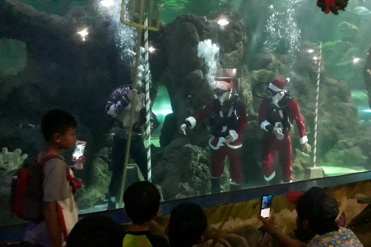 Tiga orang penyelam berkostum Aquaman dan Santa Claus menyapa pengunjung SeaWorld Ancol, Selasa (18/12/2018).