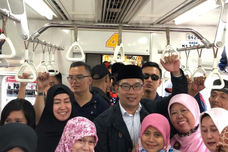 Kandidat gubernur Jawa Barat, Ridwan Kamil, saat berfoto bersama penumpang di KRL Commuter Line di Kabupaten Bekasi, Selasa (27/2/2018).
