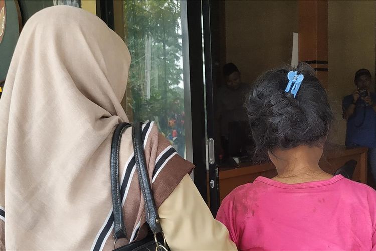 Am (kanan) didampingi kerabatnya di Polsek Cikidang, Sukabumi, Jawa Barat, Senin (15/7/2019).