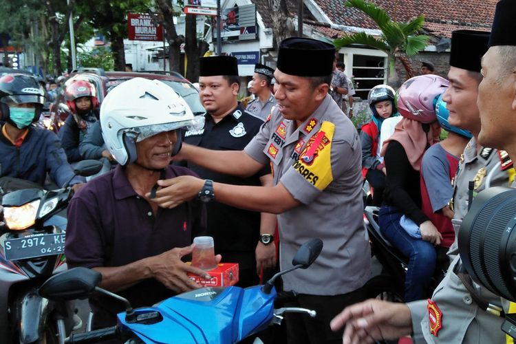 Kapolres Lamongan AKBP Feby DP Hutagalung didampingi Kasat Lantas Polres Lamongan AKP Argya Satrya Bhawana, saat membagikan takjil dan helm gratis kepada pengendara sepeda motor. 